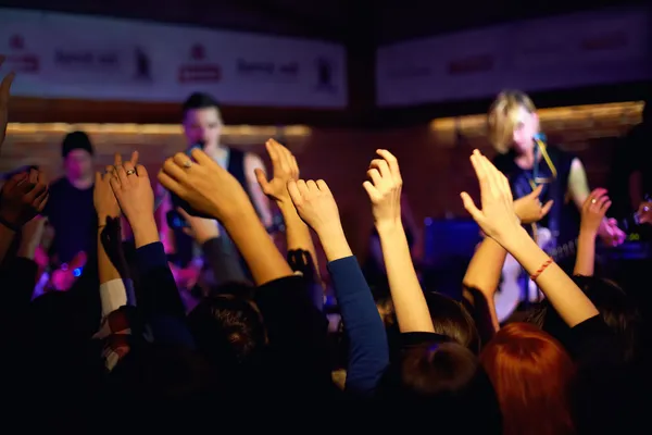 Youth waving hands on concert in night club