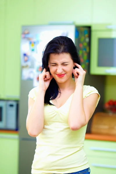 Mad woman closes ears with fingers, home interior