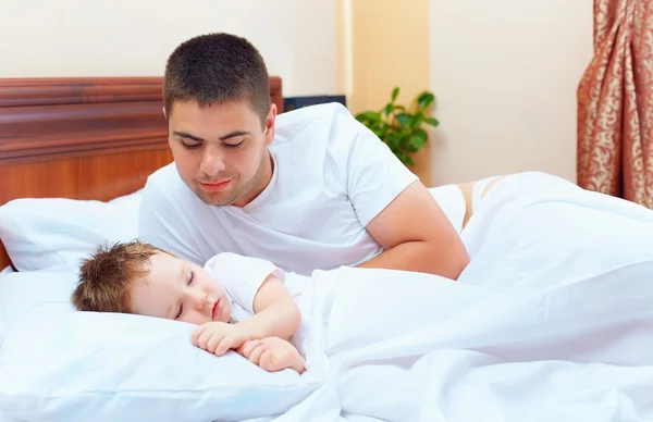 Smiling father watching the son sleeps