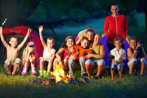 Happy kids having fun around camp fire