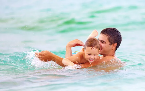 Happy father and son swimming in sea water