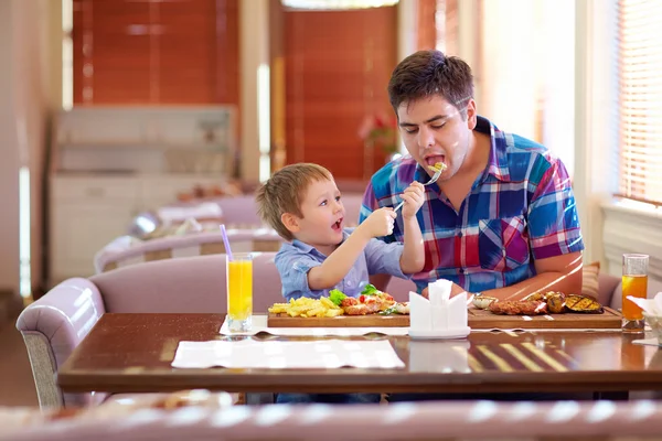 Boy feeding father in restaurant