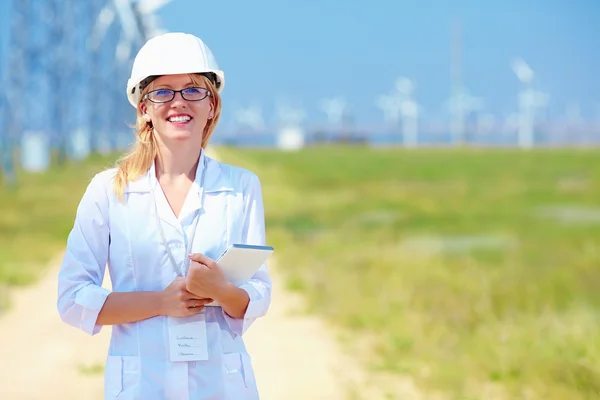 Young female researcher analyzes readouts on wind power station