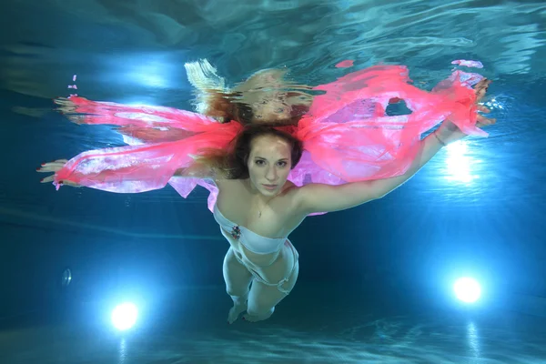 Young woman underwater with pink foulard