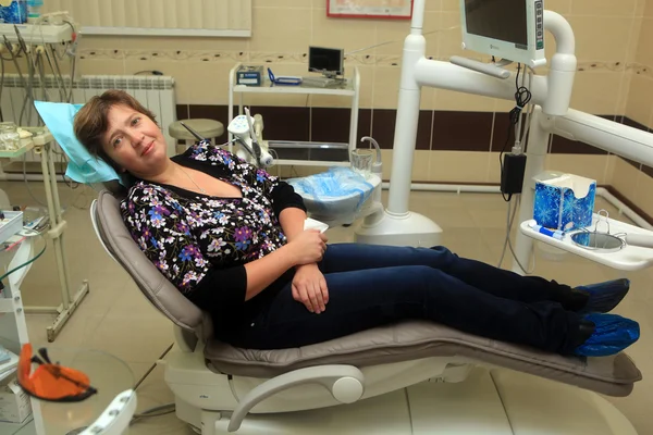 The woman sits in a stomatologic chair waiting for treatment
