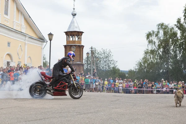 Motorcycle Show on Cathedral Square in village Verkhovazhye, Vologda Region, Russia. Alexei Kalinin burneth his motorcycle tires