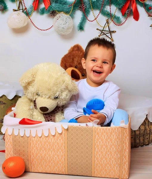 Laughing baby in the box with a bear in a Christmas setting