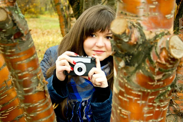 Girl with camera behind a tree