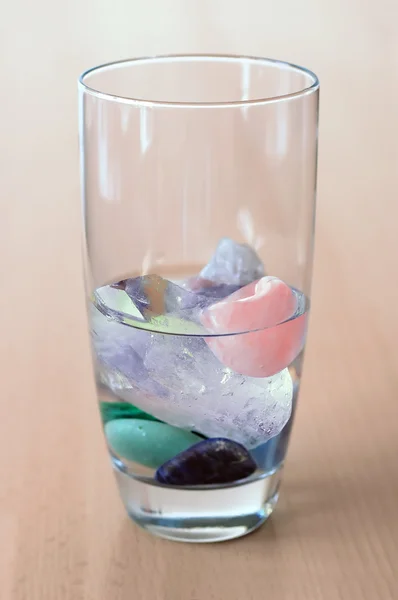 Crystals in glass of water on wooden table