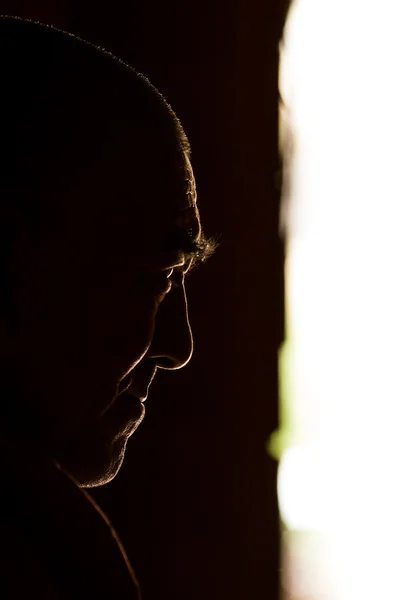 Profile head of a monk in backlit conditions during meditation i