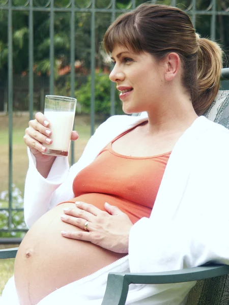 Young pregnant woman drinking milk outdoor