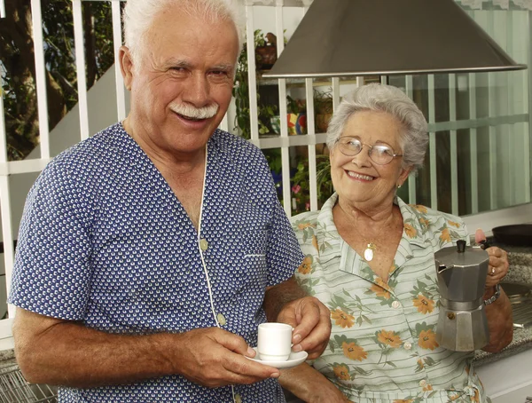 Happy grandparents couple drinking coffee in the kitchen.