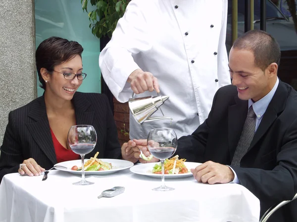 Hispanic couple at a restaurant and a waiter serving.
