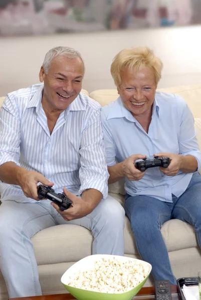 Senior couple playing video games holding joysticks.