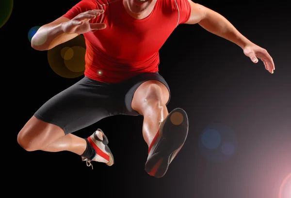 Athletic fitness man jump on black background.