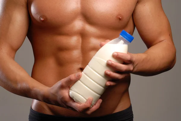 Shaped and healthy body man holding a milk bottle.