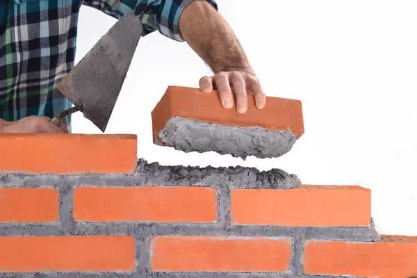 Constructor hand holding a brick and building a wall.