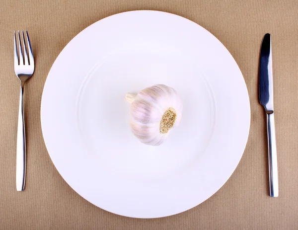 Garlic on a white plate with fork and knife