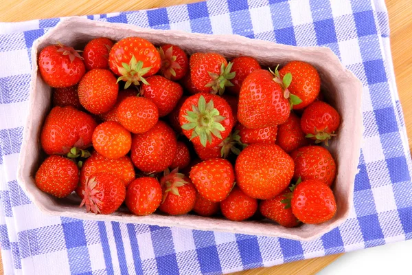Fresh strawberry in paper box on white-blue background