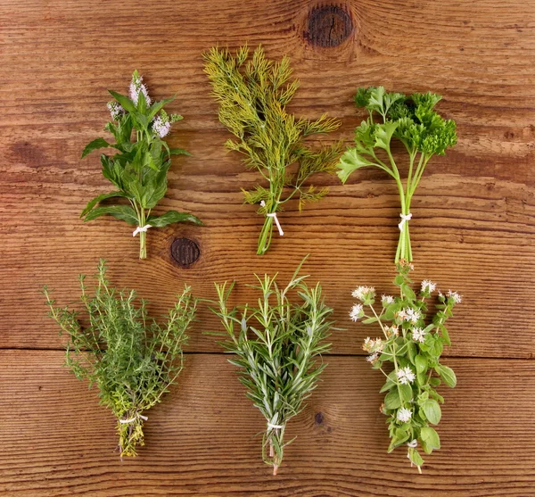 Herbs in bundle on brown wooden background, close up