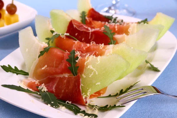 Ripe melon with ham, parmesan on white plate, cheese