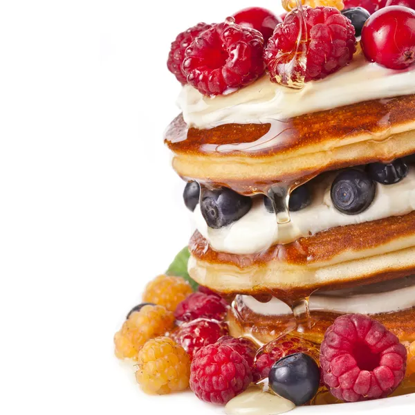 Pancakes stack with fresh berries on white background