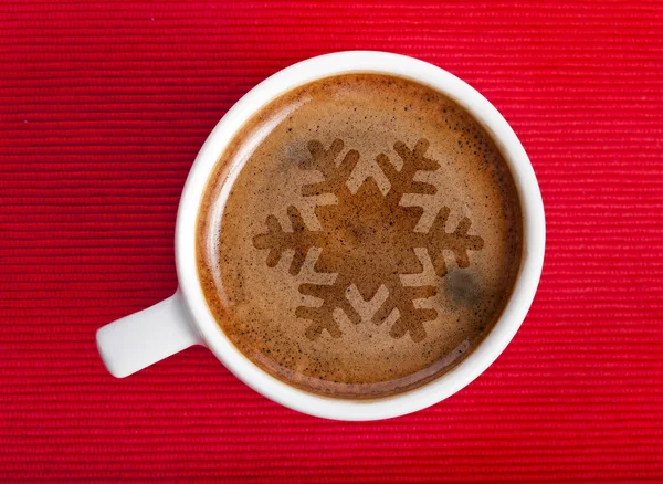 Coffee cup with christmas snow flake on red napkin background