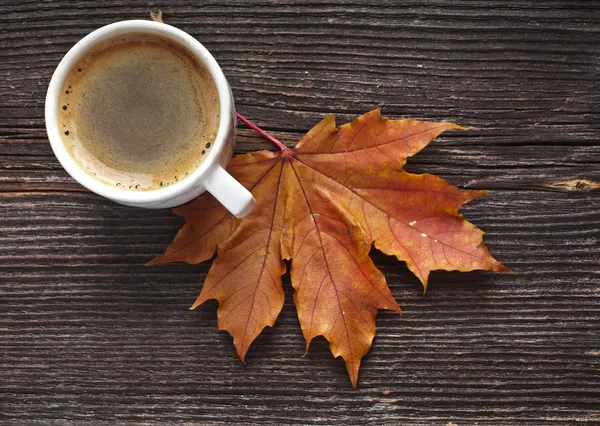 Coffee cup on the autumn fall leaves and wooden surface background