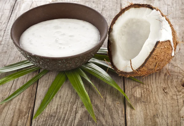 Cracked coconut with milk cream in a clay bowl on wooden table