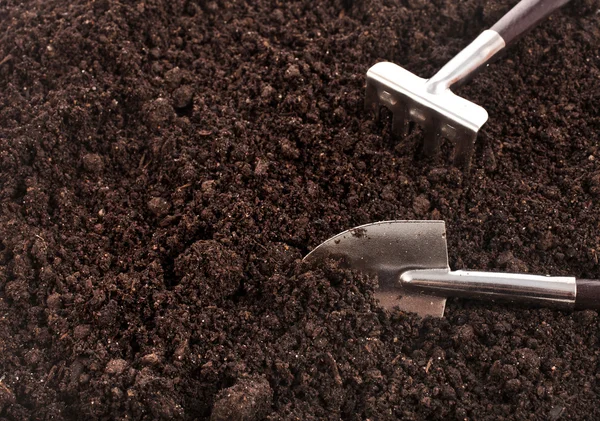 Close up of organic soil surface background with gardening tool