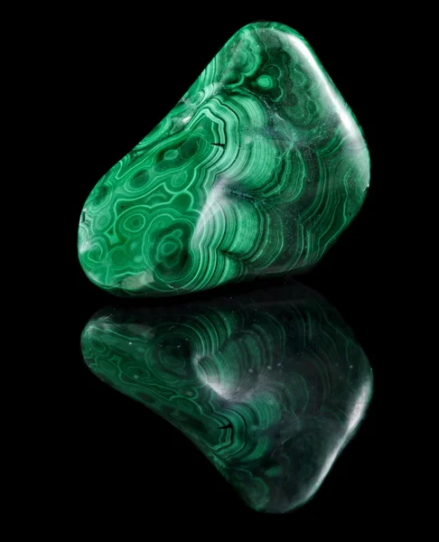 Polished malachite stone close up with reflection on black surface background