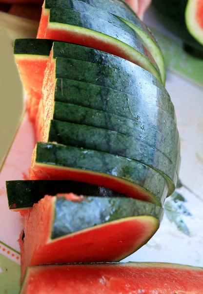 Watermelon fruit sliced pieces on the wooden floor.