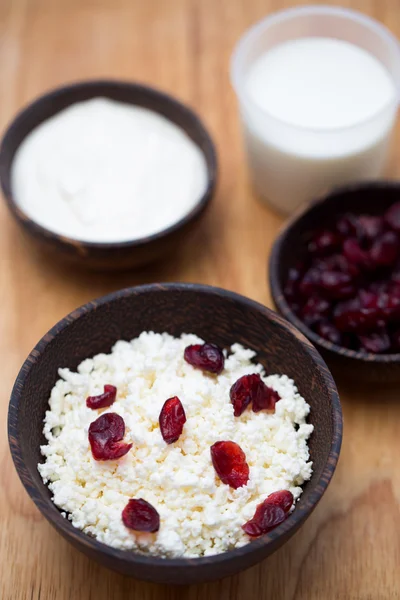 Milk, sour cream, cottage cheese and dried cranberries on a wooden table