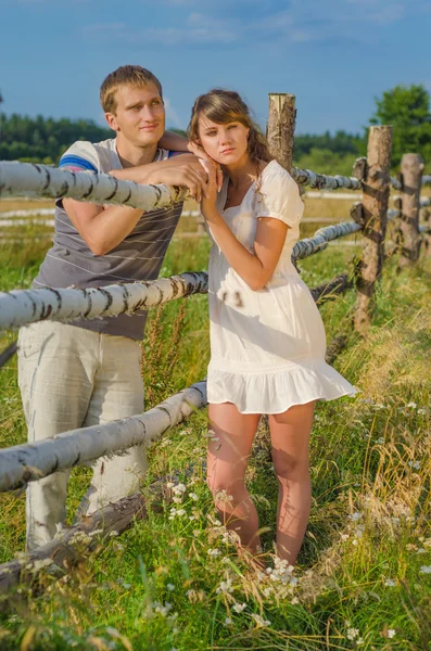 Young loving couple standing in the sun near a fence