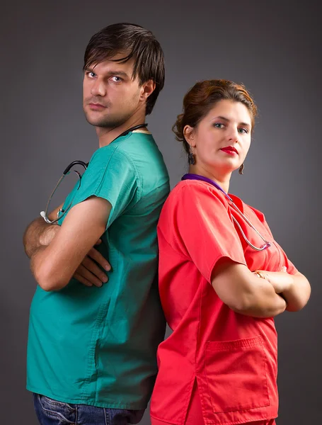 Serious team of two doctors standing back to back with arms fold