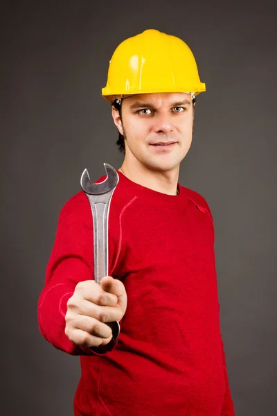 Portrait of a smiling young man holding a wrench