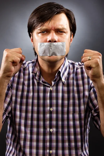 Angry young man with duct tape over his mouth