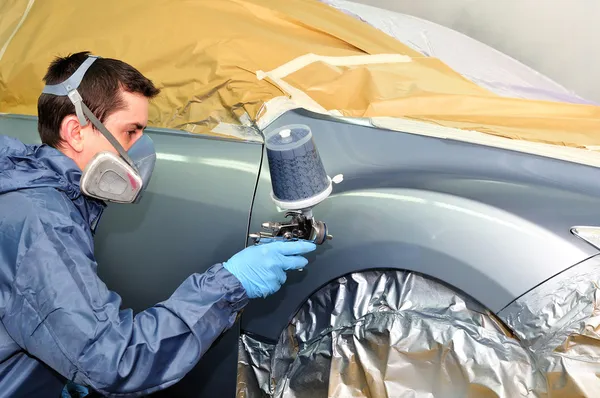 Worker painting a car.