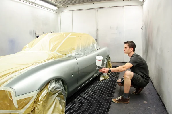 Worker painting a car