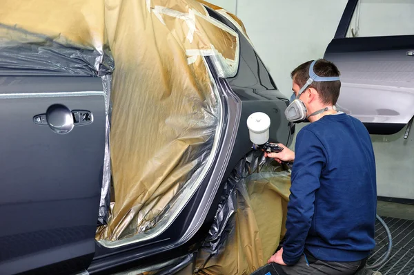 Worker painting a car