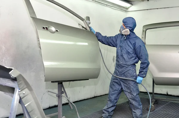 Worker painting car door.