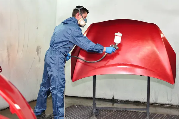 Worker painting a red bonnet.