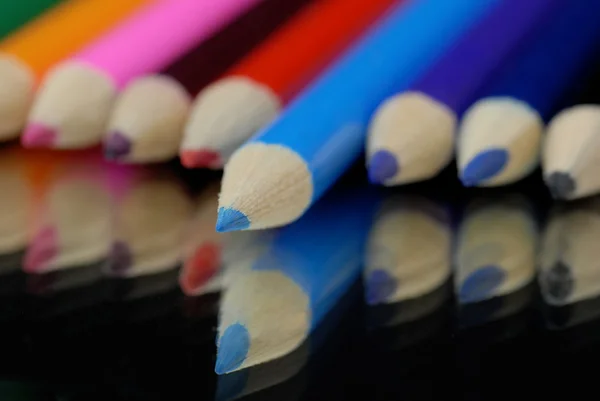 Blue pencil crayon sticking out among several other bright pencil crayons