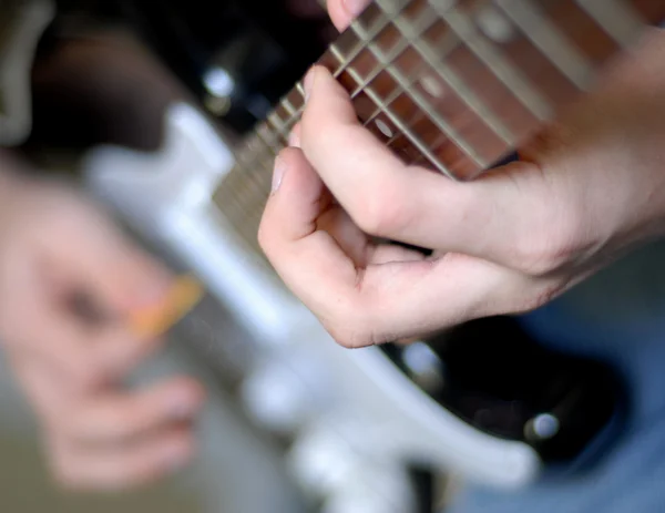 Hands on frets of guitar with shallow depth of field