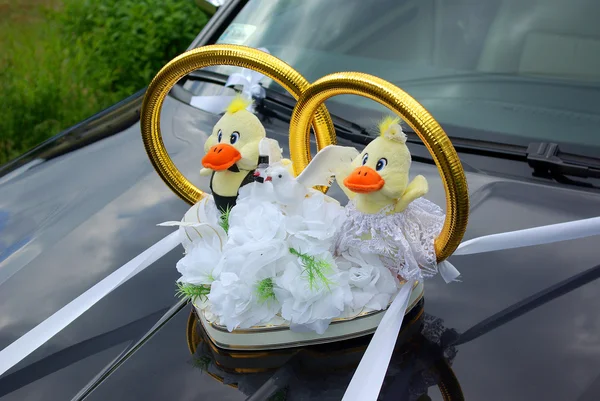 Wedding limousine decorated with flowers and gold rings