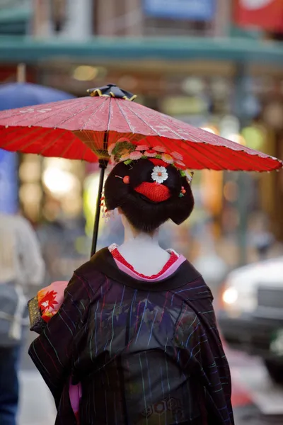 Geisha with red umbrella in Kyoto, Japan