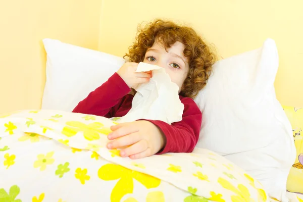 Sick child in bed blowing her nose