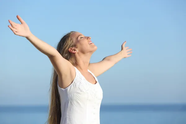 Attractive blonde woman breathing happy with raised arms