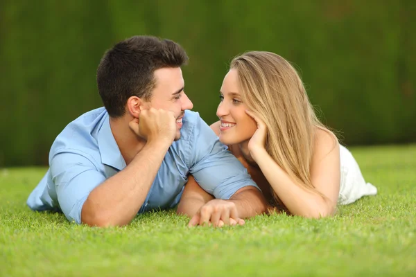 Couple in love dating and looking each other lying on the grass