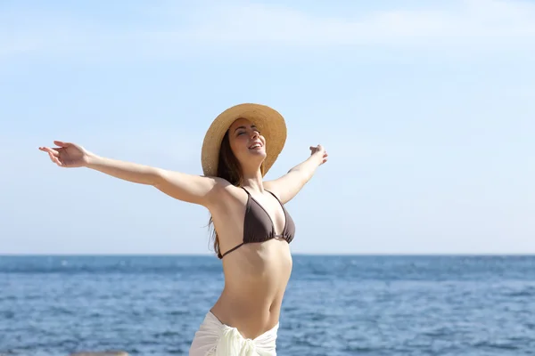 Happy woman breathing fresh air on the beach raising arms